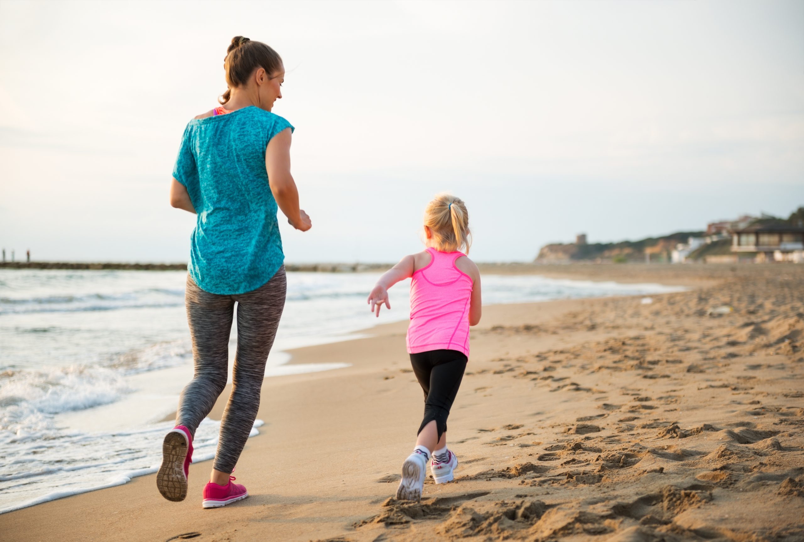 Woman running on the beach with her daughter